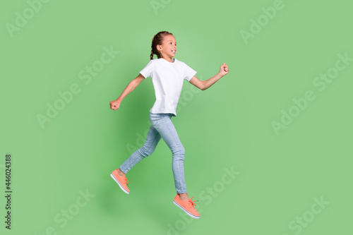 Full length body size photo little girl jumping up running fast isolated pastel green color background © deagreez