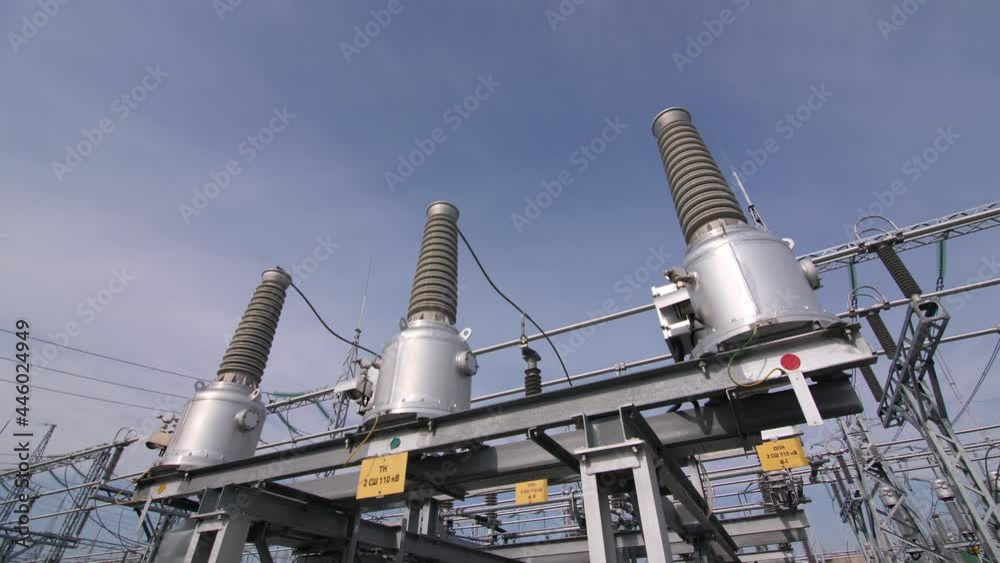 Modern equipment with ceramic insulators and cables at electricity production substation under blue sky close view Modern equipment with ceramic insulators and cables at electricity production substation under blue sky close view