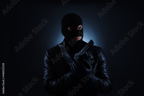 Man wearing knitted balaclava with gun on black background