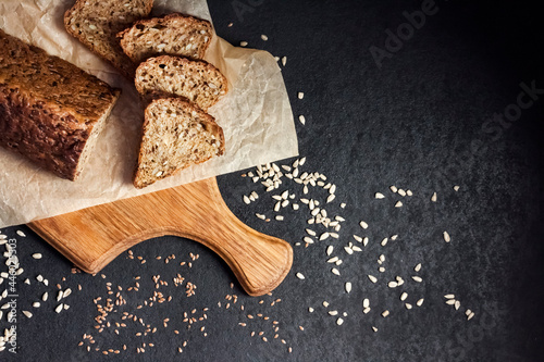 Bread with sunflower and flax seeds on a wooden cutting board on a black background