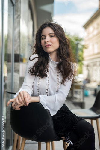 pretty woman sitting near cafe in city centre and posing, enjoy summer lifestyle