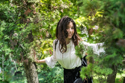 portrait of a woman wear white blouse and stylish black skirt near green tree