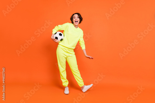 Fototapeta Naklejka Na Ścianę i Meble -  Full length body size view of attractive cheerful girl holding ball having fun isolated over bright orange color background