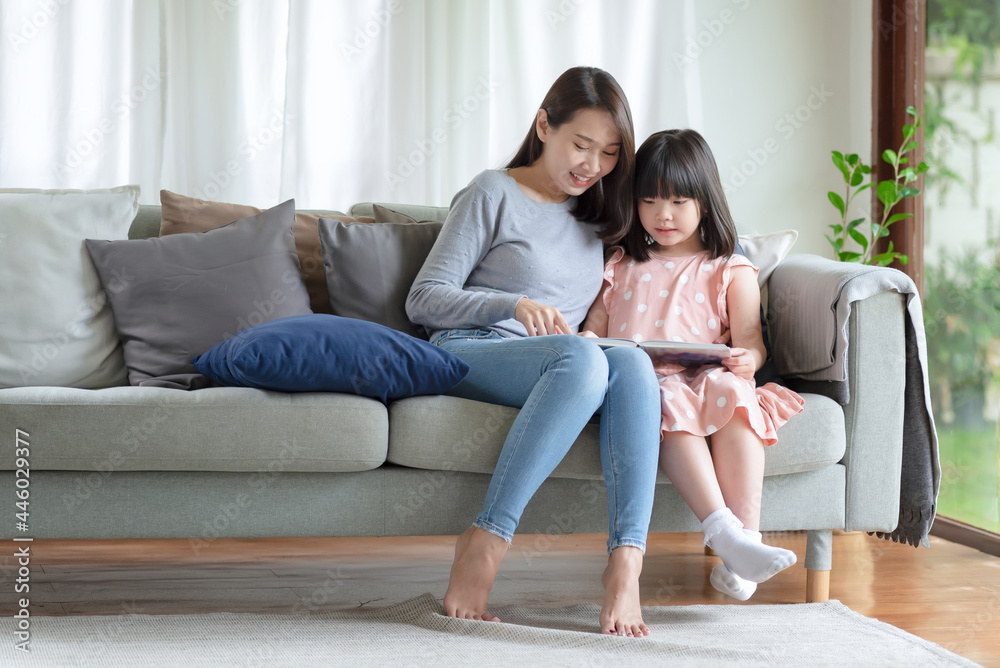 Happy asian mother teaching her cute kid daughter to studying in living room at home Happy asian mother teaching her cute kid daughter to studying in living room at home