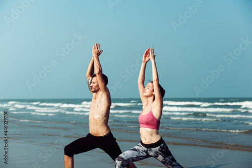 Couple doing yoga by the beach