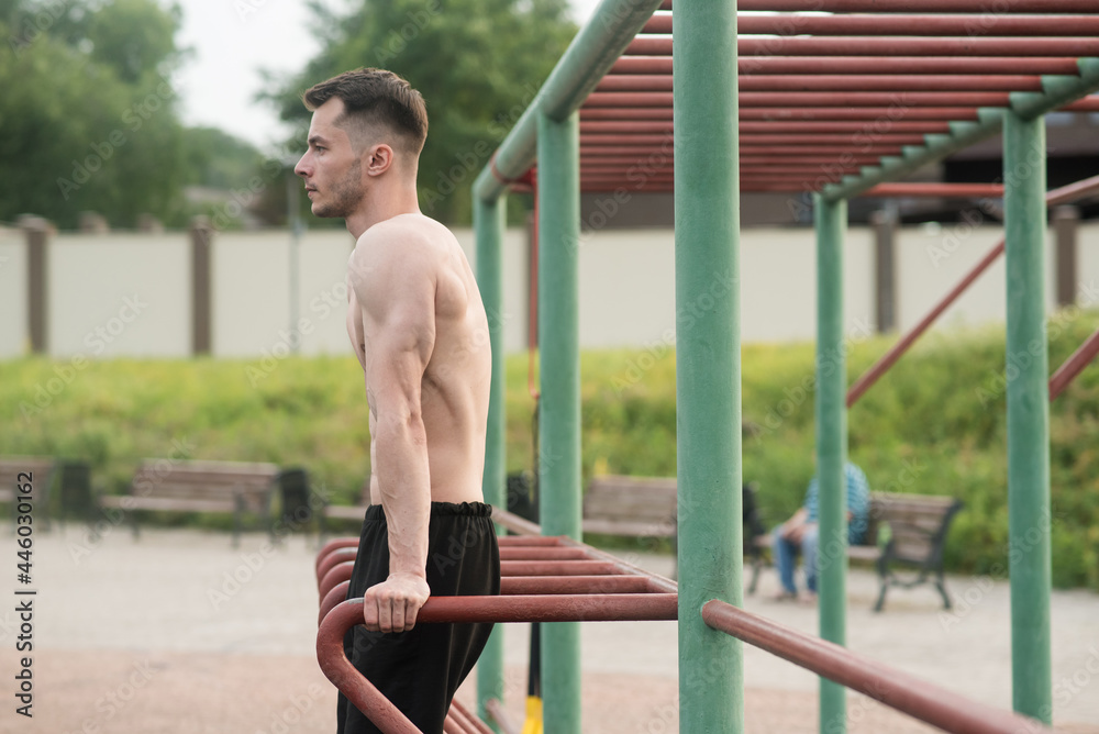 Obraz premium Young attractive Caucasian man doing push ups on the bars. Workout concept