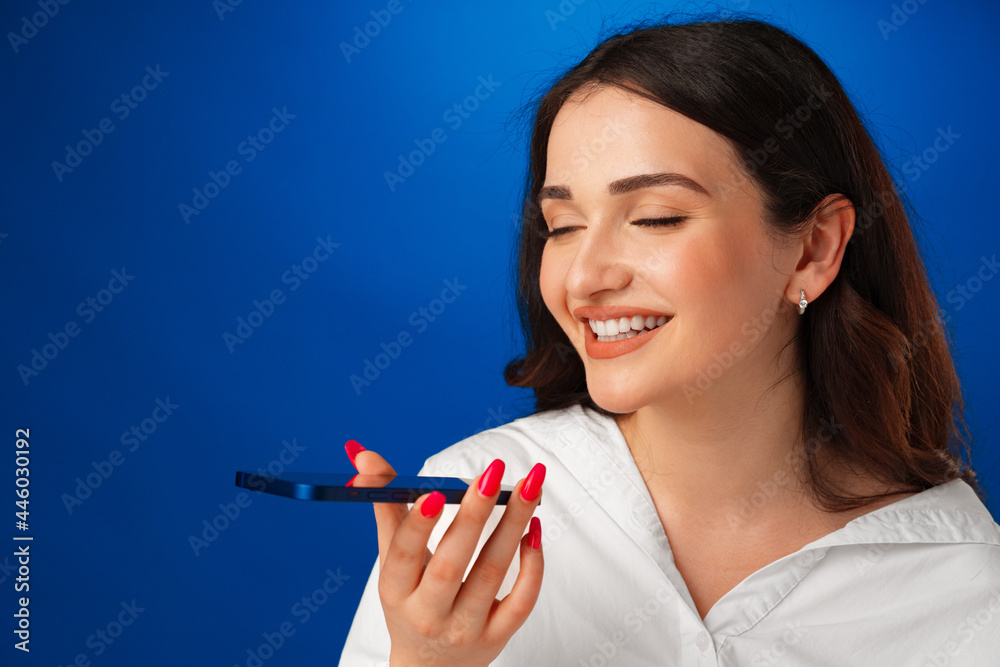 Young brunette woman talking on the phone against blue background Young brunette woman talking on the phone against blue background