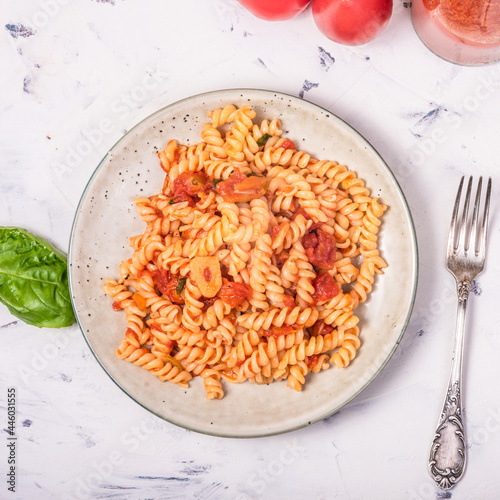 Vegetarian girandole pasta with red tomato sauce - portion in a plate on the table, top view