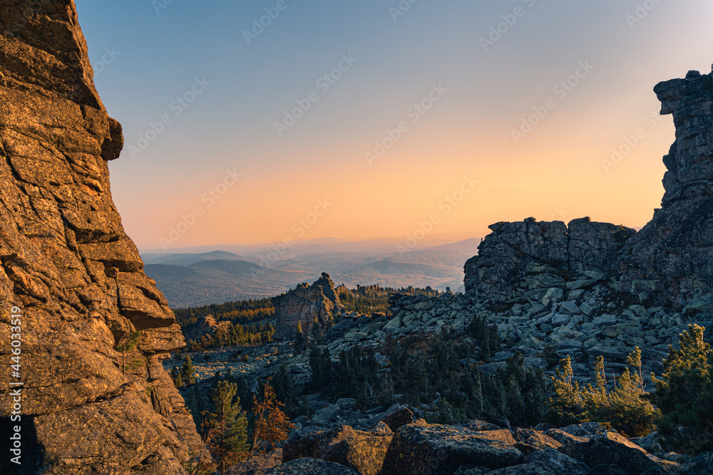 Panorama of a rocky valley in sunlight at the top of a mountain. Mountain range against the blue sky at sunset.