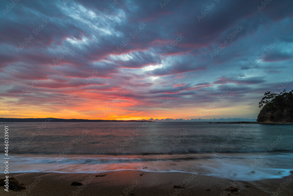 Cloud covered sunrise seascape tinged with pink