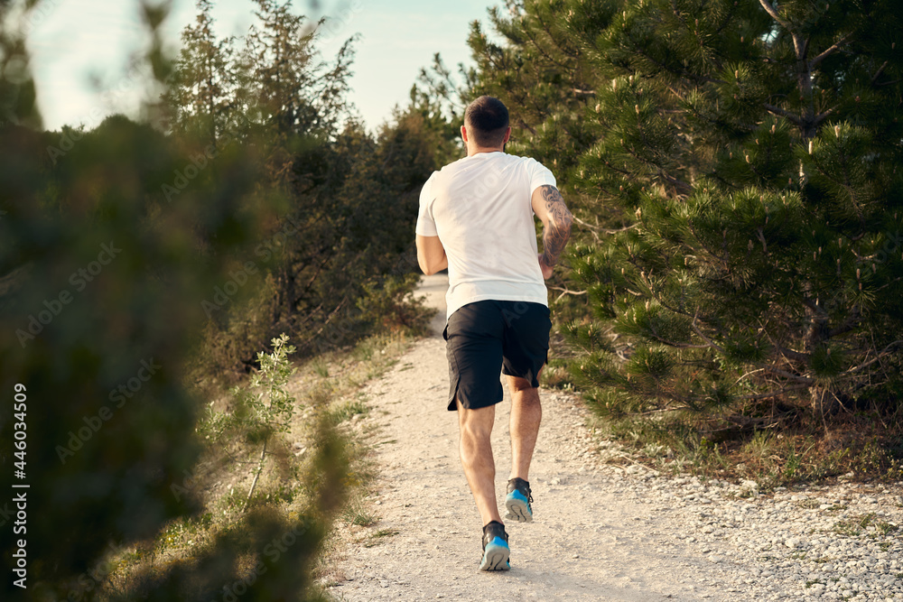 Young muscular male athlete running up the hill