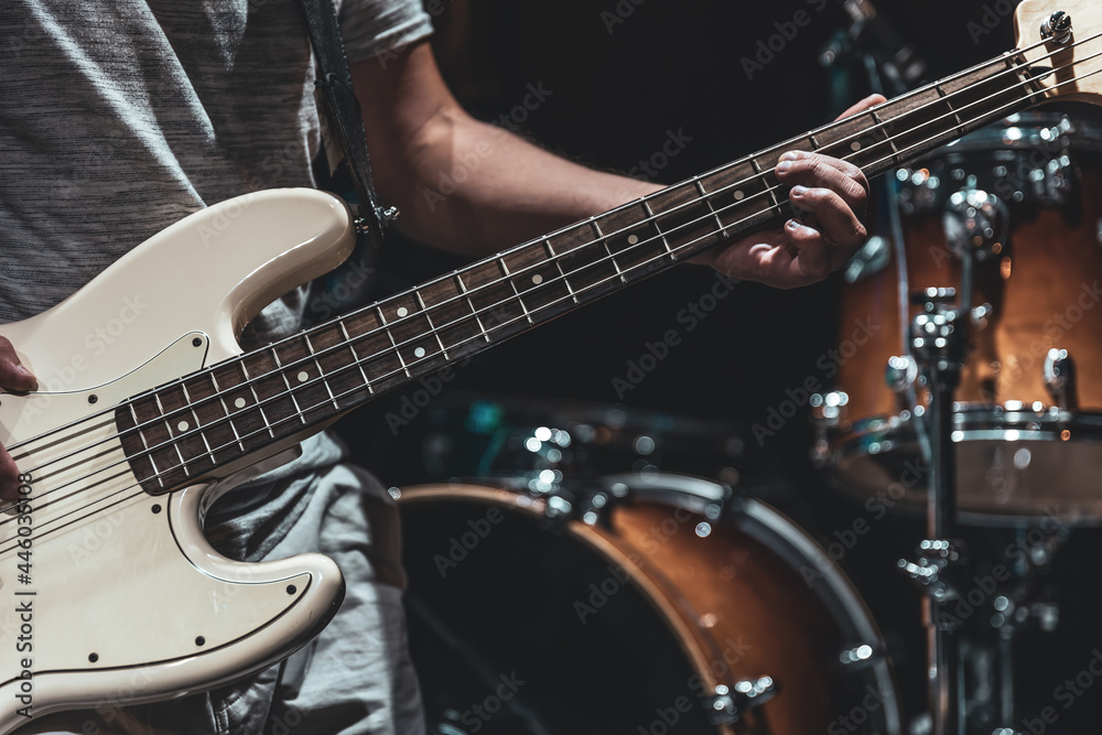 Fototapeta premium A man plays the bass guitar on a blurred background with bokeh.