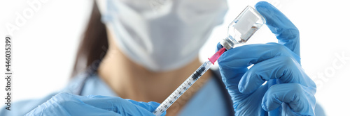 Doctor drawing medicine into syringe from vial closeup