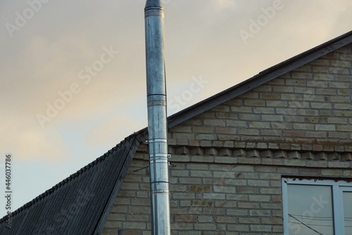 one gray long metal pipe chimney on a brown brick loft against the sky