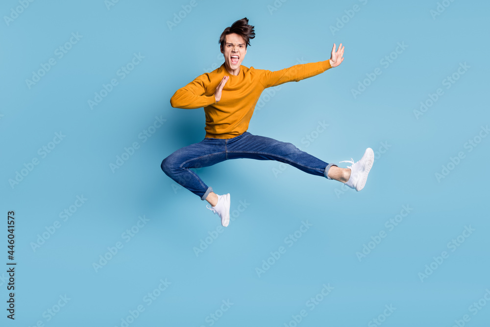 Full body photo of impressed brunet millennial guy fight wear sweater jeans isolated on blue color background Full body photo of impressed brunet millennial guy fight wear sweater jeans isolated on blue color background