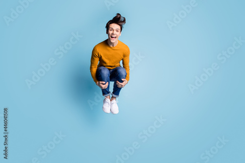 Full size photo of cool brunet young guy jump bomb into water pool wear sweater jeans isolated on blue color background