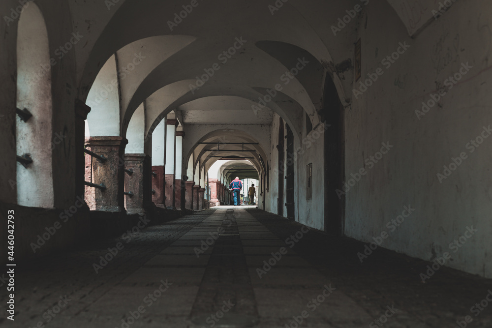 arcade passageway in small town, walking people seen from behind arcade passageway in small town, walking people seen from behind