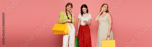 Body positive women with shopping bags talking on smartphones on pink background, banner