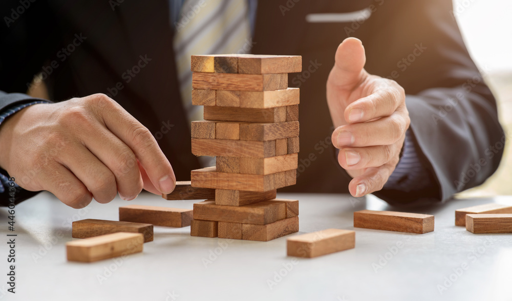 Close up hand of Business has piling up and stacking a wooden block.Businessman Building The Success,plan and strategy in business,risk concept. Close up hand of Business has piling up and stacking a wooden block.Businessman Building The Success,plan and strategy in business,risk concept.