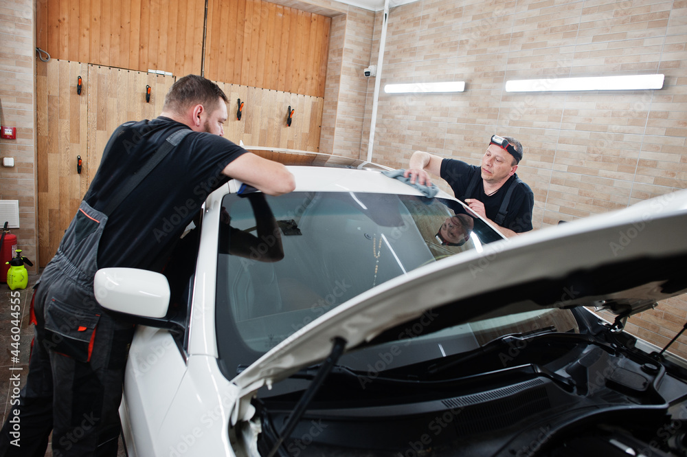 Worker in detailing garage put polyurethane anti-gravel film cover in white luxury car. Worker in detailing garage put polyurethane anti-gravel film cover in white luxury car.