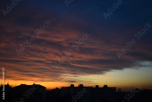 Dramatic orange clouds at sunset with city buildings silhouettes
