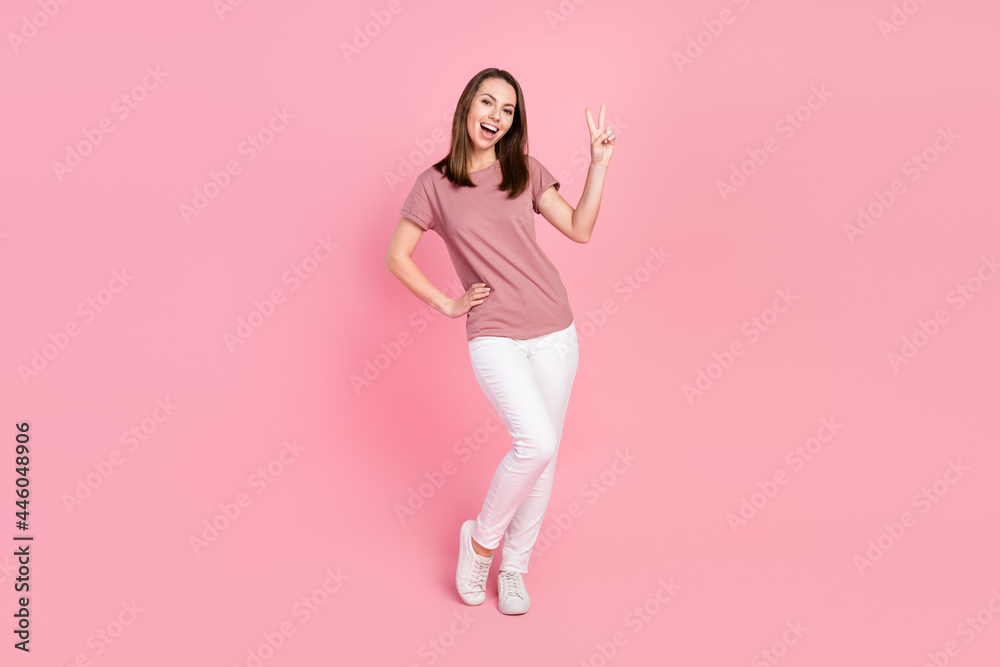 Full length body size view of attractive cheerful lucky girl showing v-sign isolated over pink pastel color background Full length body size view of attractive cheerful lucky girl showing v-sign isolated over pink pastel color background