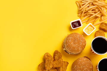 Different fast food on yellow background, flat lay. Space for text