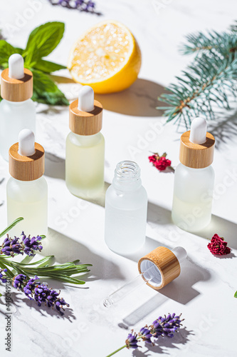 Different types of essential oils in glass bottles and ingredients for making essential oils. Skin and body care concept.