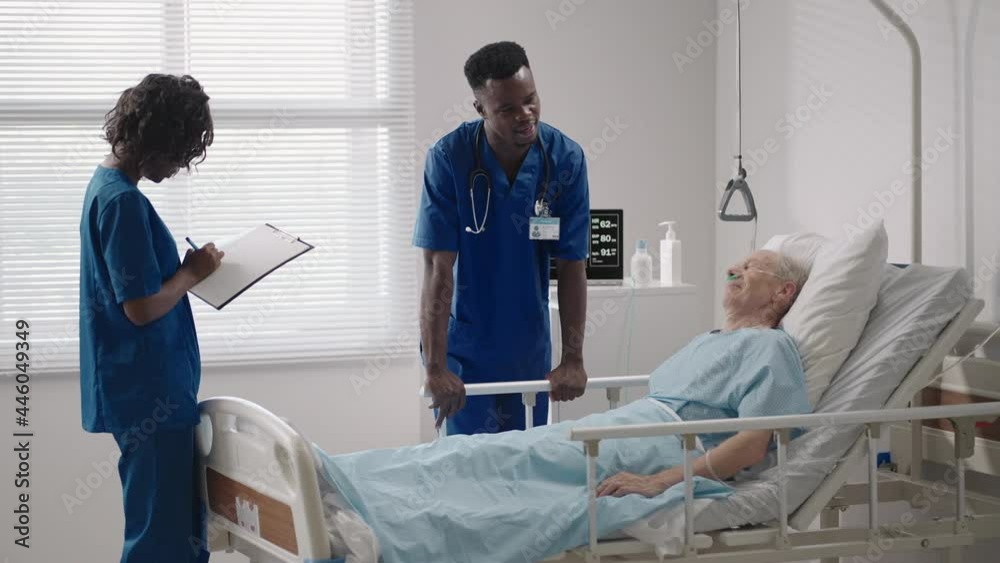 Two black doctors are talking to a patient lying in a hospital room