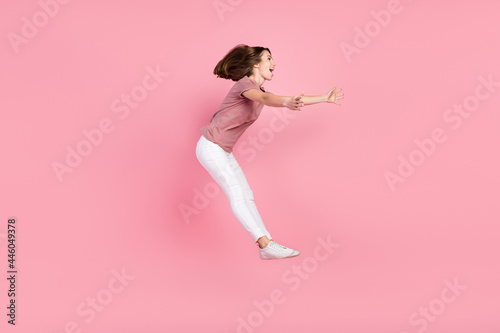 Full length body size profile side view of attractive cheerful girl jumping catching copy space isolated over pink pastel color background © deagreez