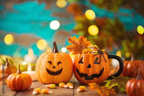 Halloween celebration concept with candy corn, jack o lantern cup, pumpkin and autumn leaves.