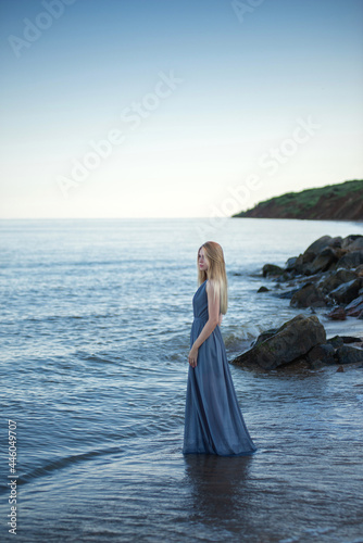 beautiful girl in a gray dress by the sea at sunset