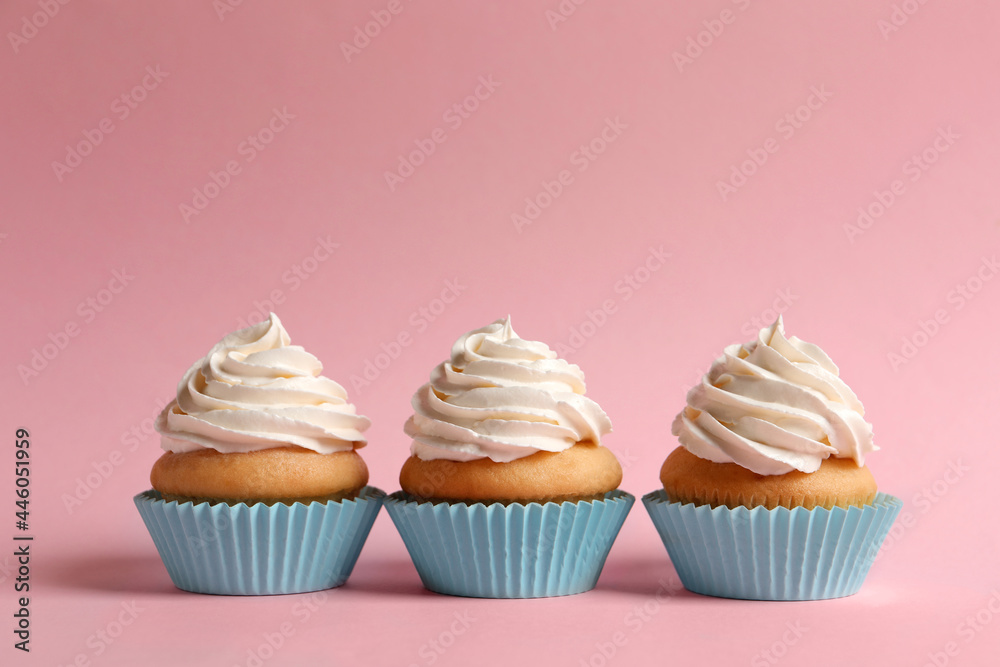Delicious cupcakes decorated with cream on pink background