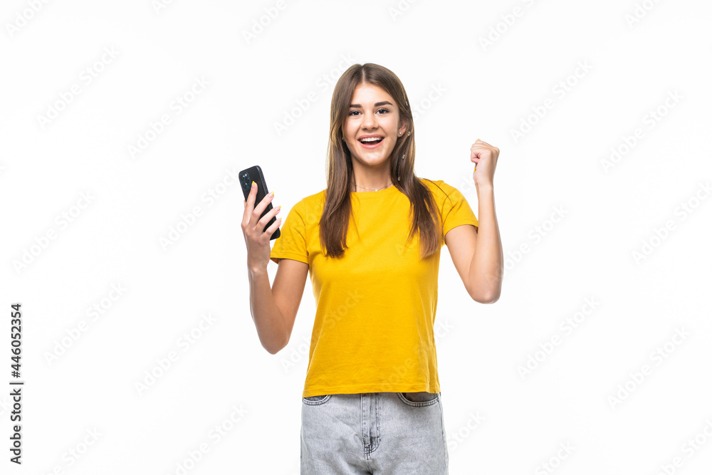 Portrait of a happy joyful girl holding mobile phone and celebrating a win isolated over white background Portrait of a happy joyful girl holding mobile phone and celebrating a win isolated over white background