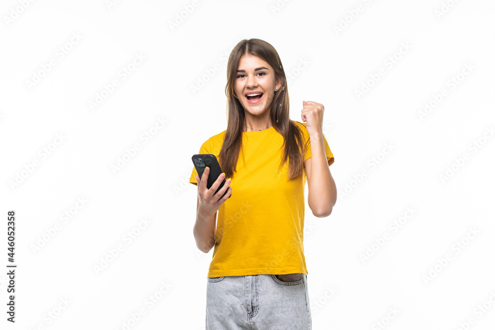 Portrait of a happy joyful girl holding mobile phone and celebrating a win isolated over white background Portrait of a happy joyful girl holding mobile phone and celebrating a win isolated over white background