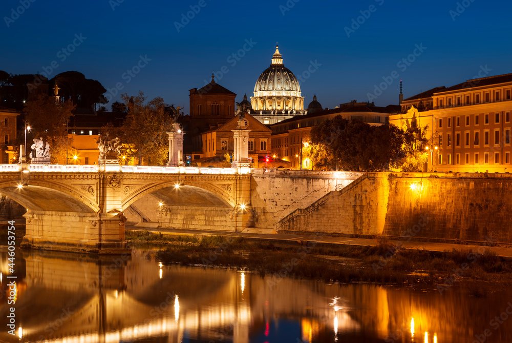 View of Rome at night with the vittorio emanuele II bridge, the dome of St. Peter's Cathedral and  their reflection in the water of the Tiber river late in the evening. Italy