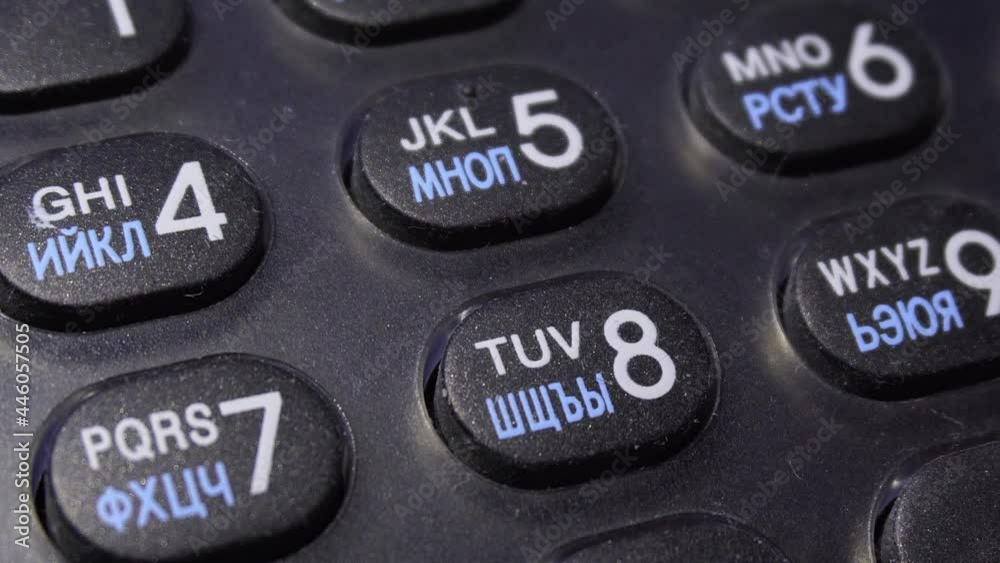 Close up of numerical dial buttons on an old analog phone. Dailing number on a black telephone, with finger pressing on the numerical buttons. Close up of numerical dial buttons on an old analog phone. Dailing number on a black telephone, with finger pressing on the numerical buttons.