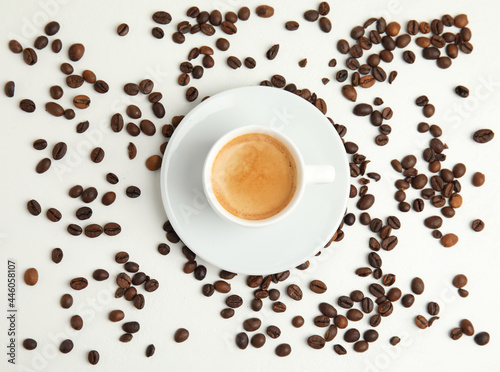 Cup of hot aromatic espresso and roasted beans on white table, flat lay