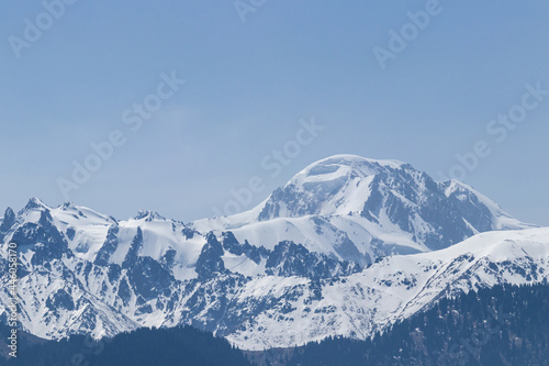 Snowy mountain peak on a sunny day with avalanches on the slope