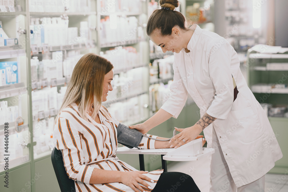 Trainee taking blood pressure of his customer in the pharmacy Trainee taking blood pressure of his customer in the pharmacy