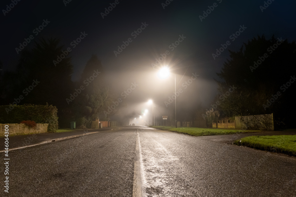 A dark moody street going into the distance on a foggy winters night. In an English town. Worcester.