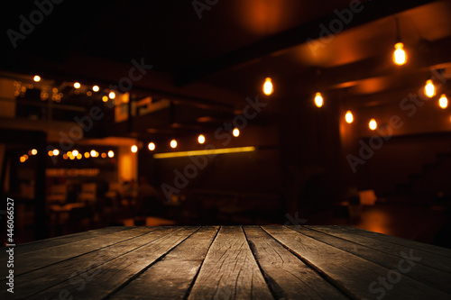 image of wooden table in front of abstract blurred background recreating lights of restaurant cafe