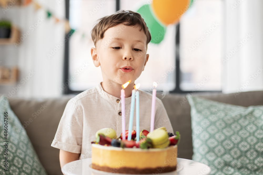 holidays, celebration and people concept - happy little boy blowing candles on birthday cake at home party holidays, celebration and people concept - happy little boy blowing candles on birthday cake at home party