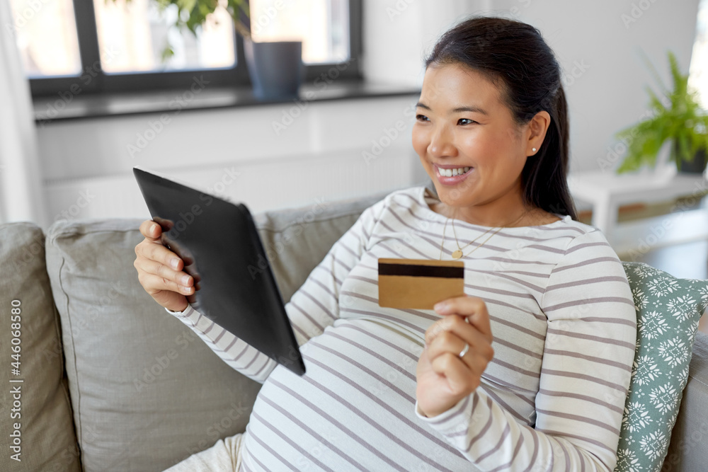 pregnancy, online shopping and people concept - happy smiling pregnant asian woman with tablet pc computer and credit card sitting on sofa at home pregnancy, online shopping and people concept - happy smiling pregnant asian woman with tablet pc computer and credit card sitting on sofa at home