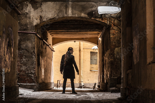 Long-haired guy stands in a snow-covered arch in a black coat