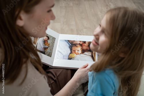 mother and daughter looking a book with photos from a family photo shoot photo