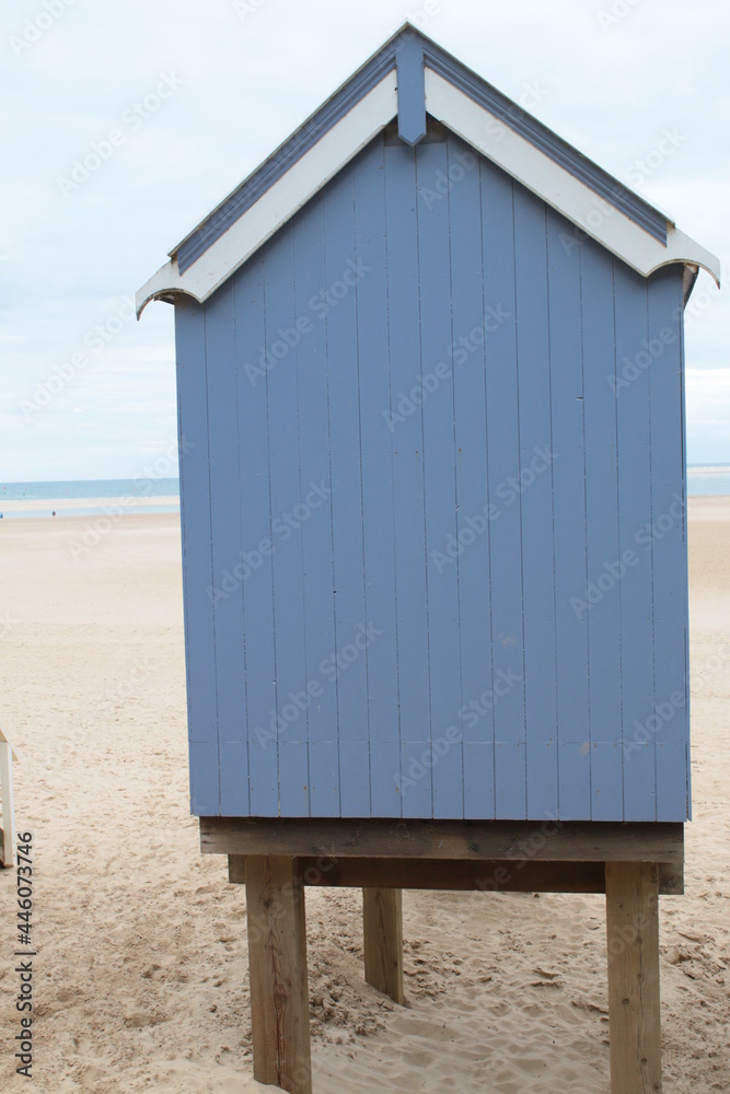 Landscape of beach huts on beautiful sandy beach coastline at Wells-Next-the-sea in Norfolk East Anglia on early Summer morning the sea on the horizon with painted wood huts foreground on holiday