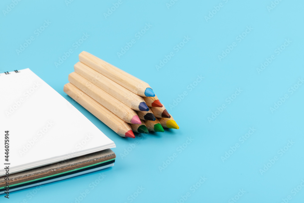 Fototapeta premium Blank paper and a colorful pencil on a blue background