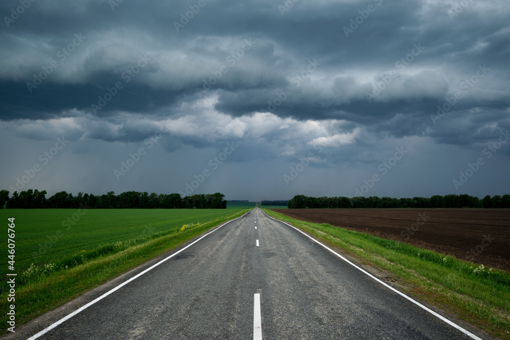 A road leading into the distance, through the sky in thunderclouds. A road leading into the distance, through the sky in thunderclouds.