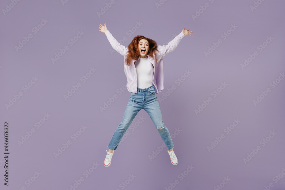 Full size body length laughing young redhead curly green-eyed woman 20s wears white T-shirt violet jacket jump spreading hands and legs isolated on pastel purple color wall background studio portrait.